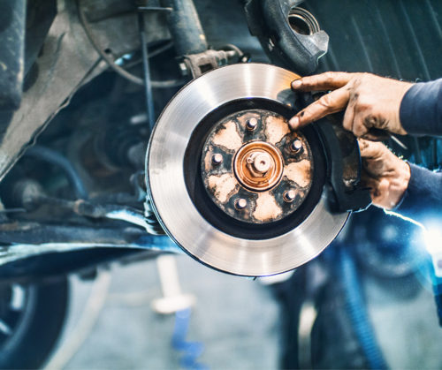 European Auto repair technician repairing brakes